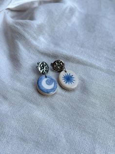 two blue and white buttons sitting on top of a white cloth