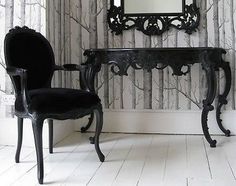 a chair sitting next to a mirror on top of a wooden table in front of a wall