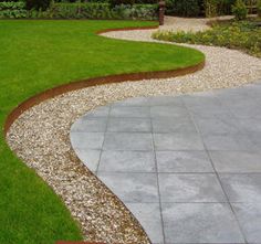 a garden with green grass and gravel in the middle