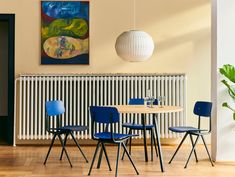 a dining room table with blue chairs next to a radiator