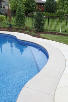 an empty swimming pool in the middle of a yard with fenced in area around it