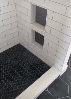 a black and white tiled bathroom with hexagonal floor tiles on the shower wall