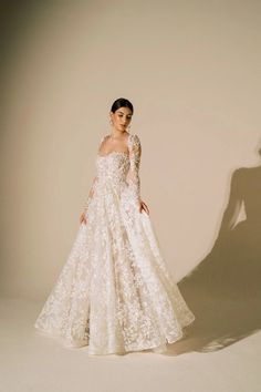 a woman in a white wedding dress is standing with her shadow on the wall behind her