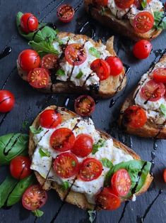 several pieces of bread with tomatoes and cheese on them, sitting on a black surface