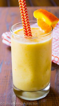 a glass filled with orange juice on top of a wooden table