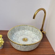 a bathroom sink sitting on top of a wooden counter next to a vase with flowers