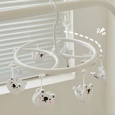 a baby crib mobile with teddy bears hanging from it's sides, in front of a window