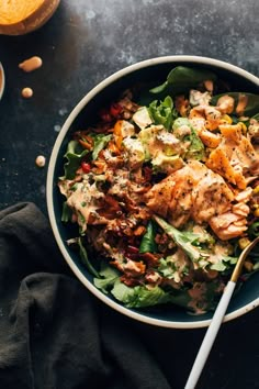 a salad with chicken and lettuce in a bowl next to some oranges