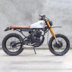 a white and orange dirt bike parked next to a wall