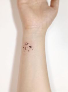 a small wrist tattoo with stars and moon on the left side of the wrist,