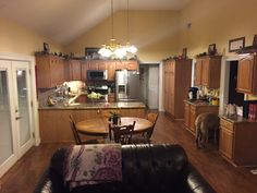 a living room and kitchen area with couches, table, cabinets and an open floor plan