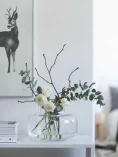 a vase filled with white flowers sitting on top of a table next to a painting