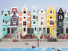 there are many colorful houses on the side of the street with ducks swimming in front of them