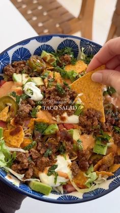 a person is holding a tortilla salad with meat, cheese and lettuce