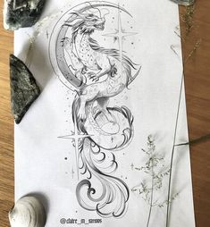 a drawing of a dragon sitting on top of a piece of paper next to some rocks