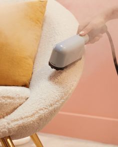 a person using a steam mop to clean a chair with a pillow on it