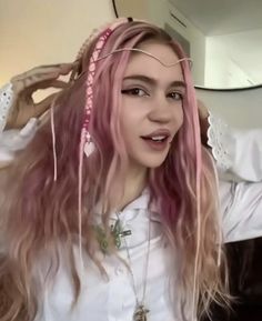 a woman with long pink hair is standing in front of a mirror