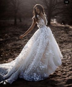 a woman in a wedding dress is standing on the ground with her arms out and hands behind her back