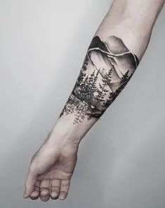 a man's arm with trees and mountains on it