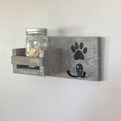 a wooden shelf with a mason jar and an animal paw print on the front, hanging from it's side