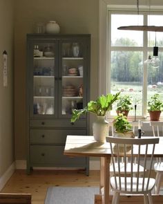 a dining room table with two chairs next to a large glass doored window that looks out onto a grassy field