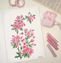 some pink flowers are sitting on a table next to markers, tape and pencils