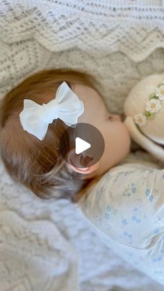 a baby doll laying on top of a bed next to a white plate with a bow