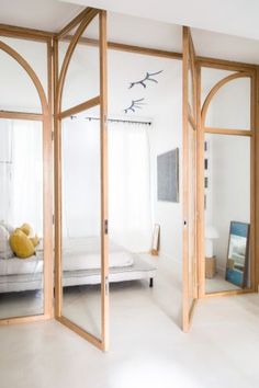 an open door leading to a bedroom with a bed in the corner and two mirrors on the wall