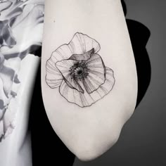 a black and white photo of a flower on the right arm, with an insect in it's center