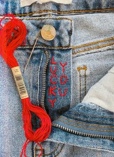 a pair of jeans with red thread in the pocket