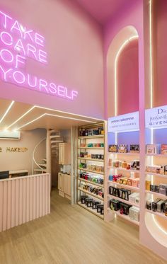 the inside of a cosmetics store with pink walls and neon signs on the wall that read, take care of yourself