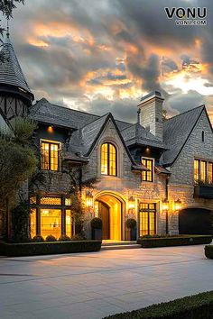 a large house with lots of windows and lights on it's front entrance at dusk