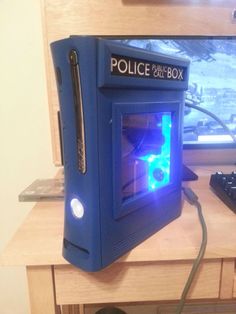 a blue police box sitting on top of a wooden table next to a keyboard and mouse