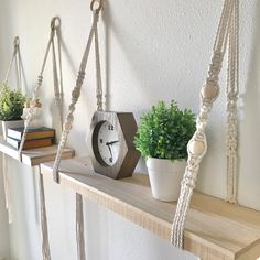 a clock, potted plant and rope hanging from a shelf in a room with white walls