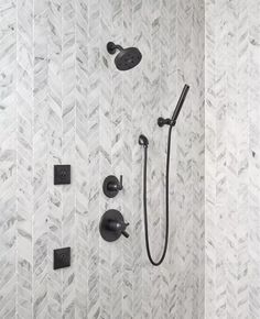 the shower head and handset are shown in this modern bathroom with herringbone tile