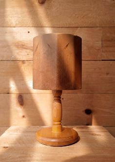 a wooden table with a lamp on it and wood planks behind the lampshade