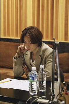 a woman sitting at a table talking on her cell phone while holding a pen to her ear