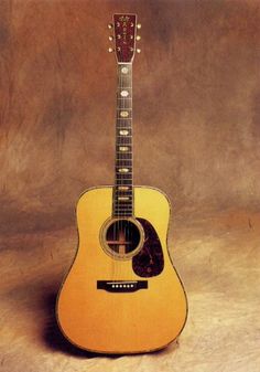 an acoustic guitar sitting on top of a brown background with the strings still attached to it