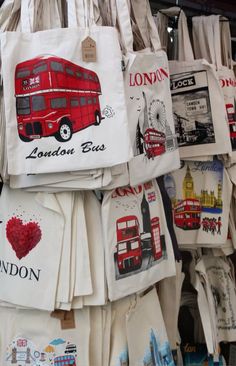 many bags are hanging on the wall with london images and words painted on them in different colors