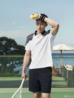 a young man holding a tennis ball and racquet on top of a tennis court