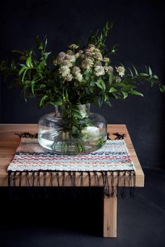 a vase filled with flowers sitting on top of a wooden table next to a rug