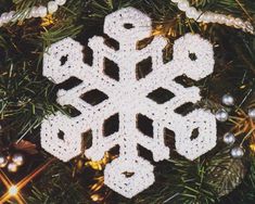 a crocheted snowflake ornament hanging from a christmas tree