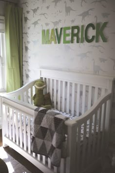 a baby's crib with a stuffed animal in it and the name maverick on the wall