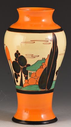 an orange and black vase sitting on top of a table