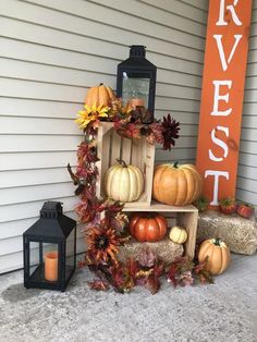 pumpkins, gourds and other autumn decorations sit on a porch next to a sign