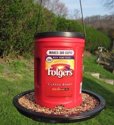 a red container hanging from a bird feeder