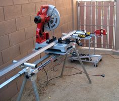 a table sawing machine sitting on top of a piece of metal next to a brick wall