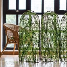 the room divider is covered with green vines and sits next to a wicker chair