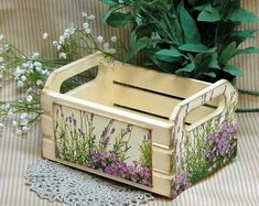 a wooden box with flowers painted on it next to a planter and doily