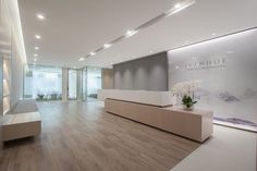 an empty lobby with white flowers in vases on the counter and large glass windows